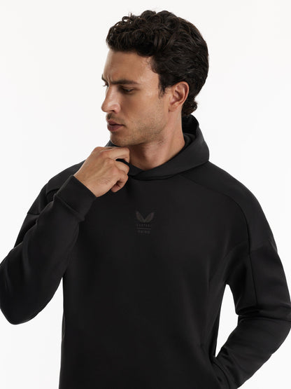 A man wearing a black pullover hoodie with a subtle tonal logo on the left chest, posed against a clean white background.