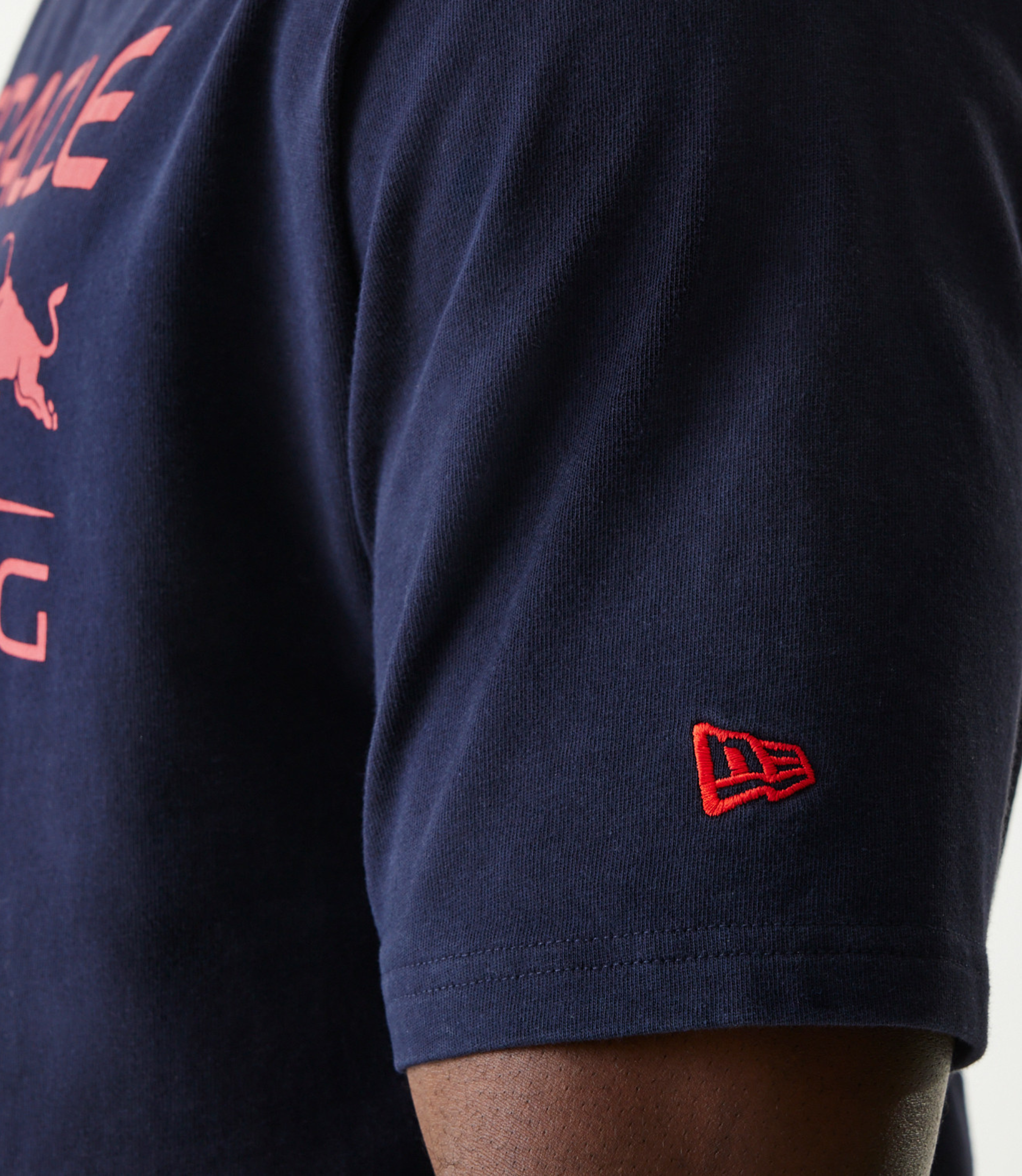 Close up of the navy T shirt sleeve with a red New Era patch and part of the Oracle Red Bull Racing print