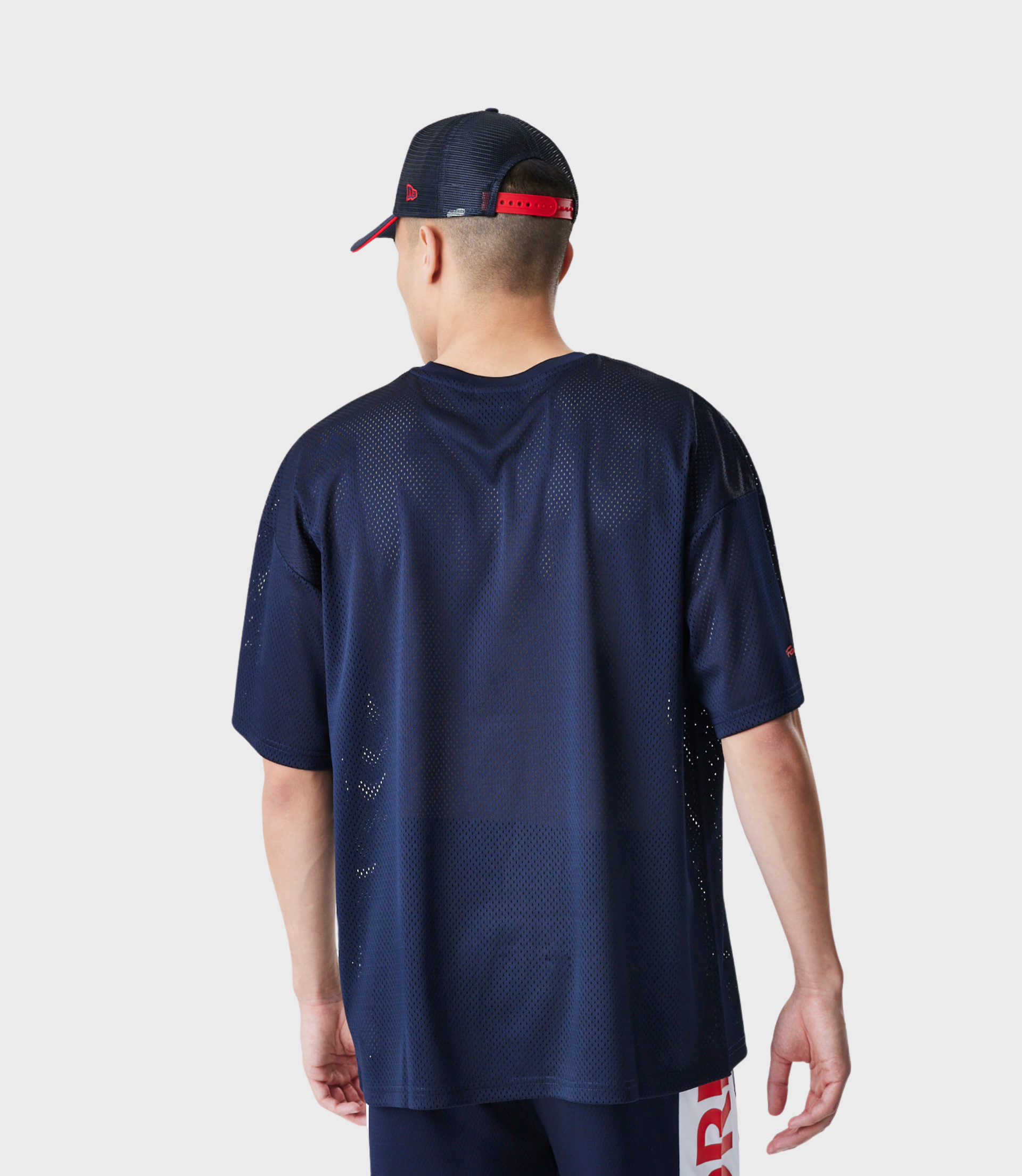 Back view of a model wearing navy mesh T shirt and matching shorts with red branding along the side seam.