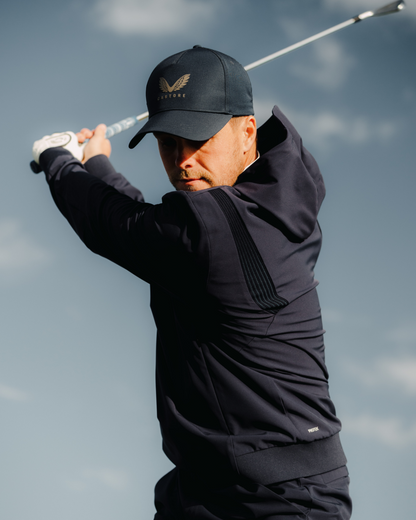 Golfer wearing the Golf Pinnacle Performance Hoodie in midnight navy mid swing with a club