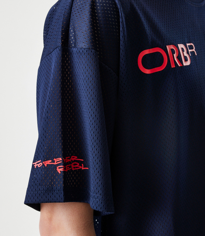 Back view of a model in a dark blue mesh T shirt, with visible pink Forever REBL lettering along the hem.