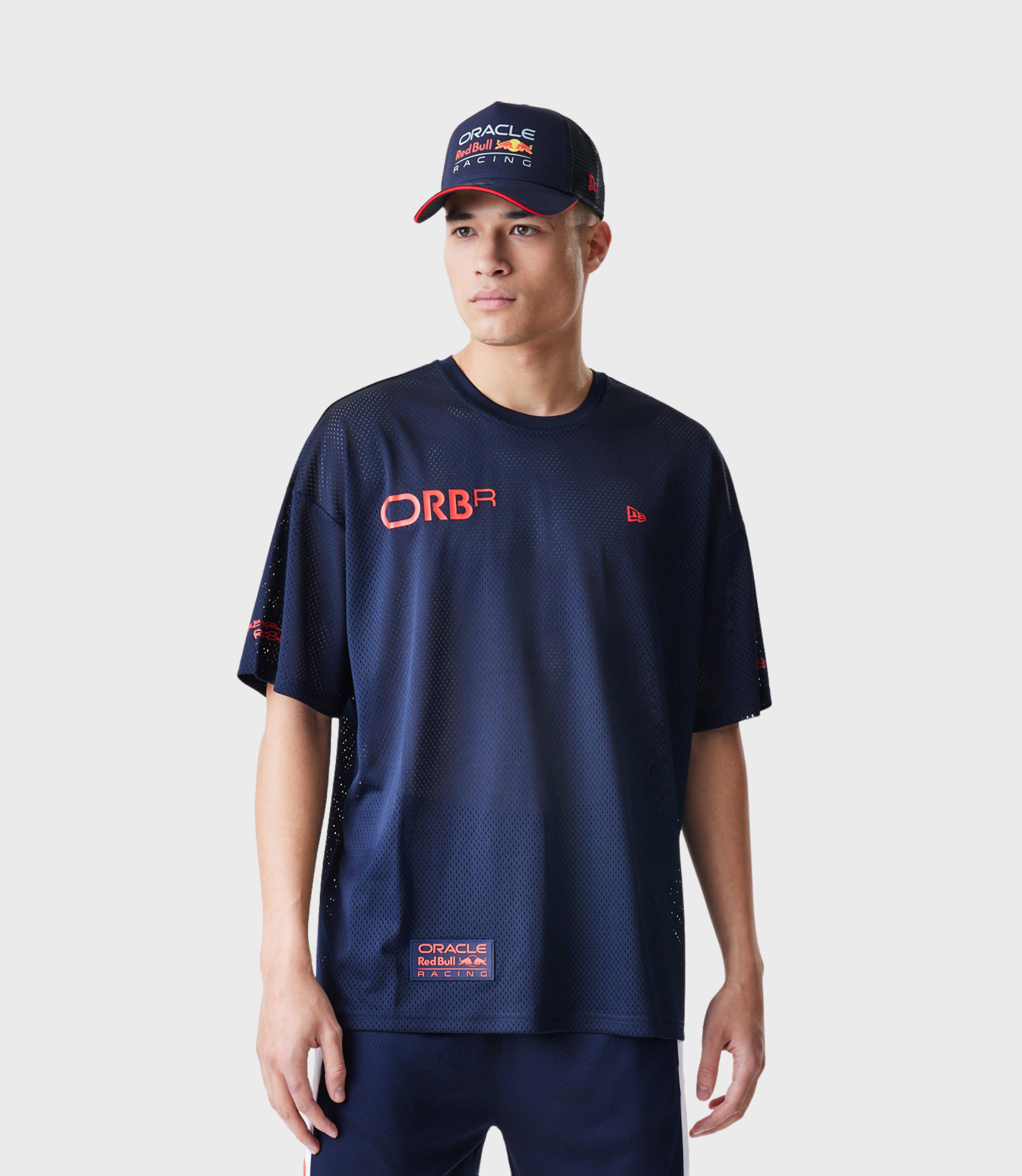 Man wearing a navy mesh T shirt with Oracle Red Bull Racing logo on chest and a navy cap with red brim