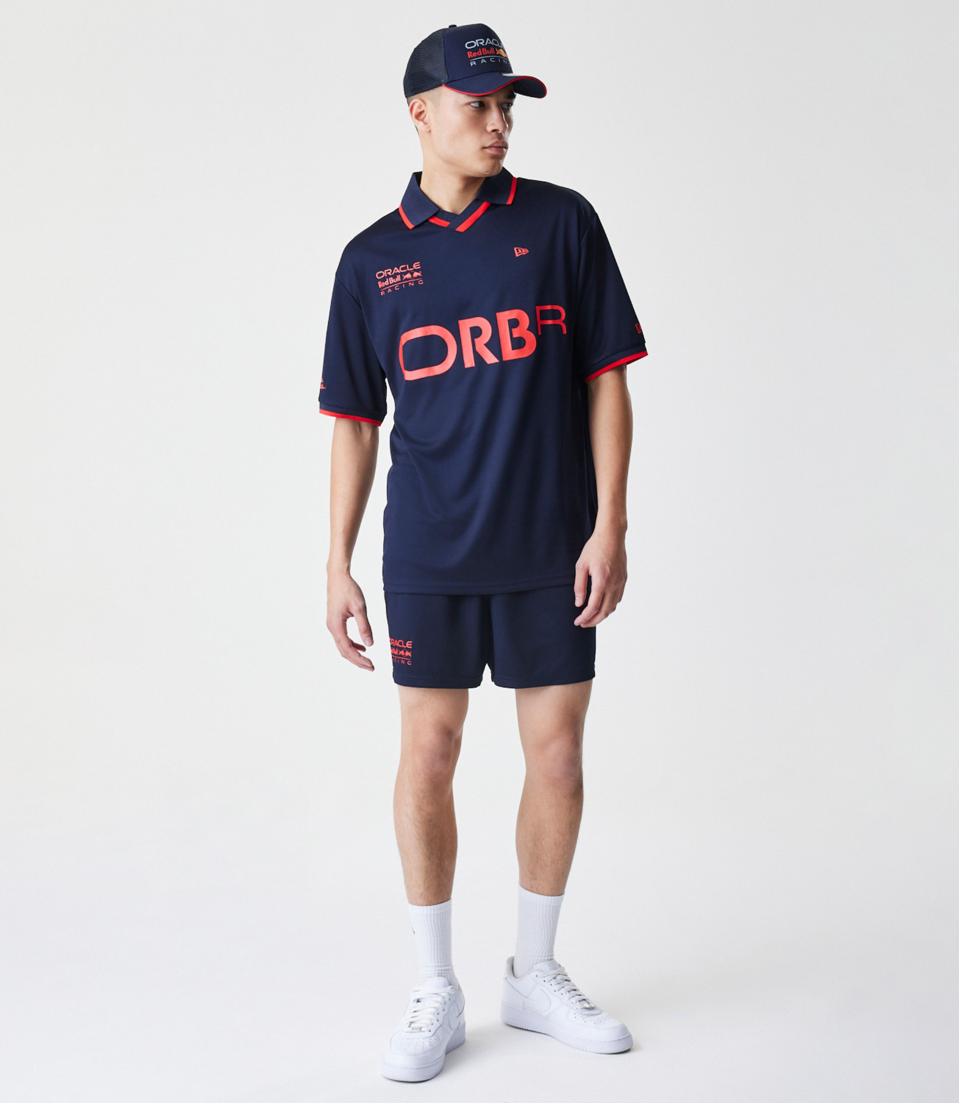 Male model in a navy Red Bull Racing football jersey with ORBR across the front and a cap branded Oracle Red Bull Racing.