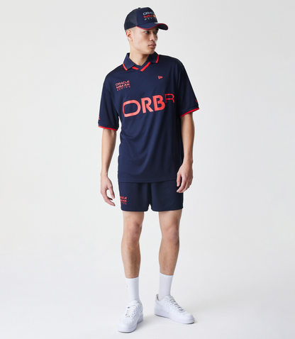 Male model in a navy Red Bull Racing football jersey with ORBR across the front and a cap branded Oracle Red Bull Racing.