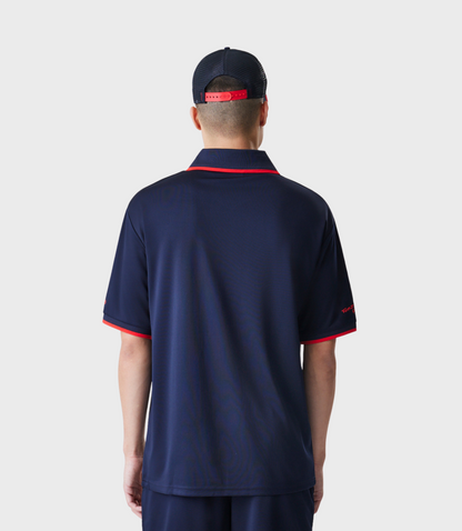 Rear view of a man in a navy polo with red trim at the collar and sleeves, featuring Oracle Red Bull Racing branding on the chest