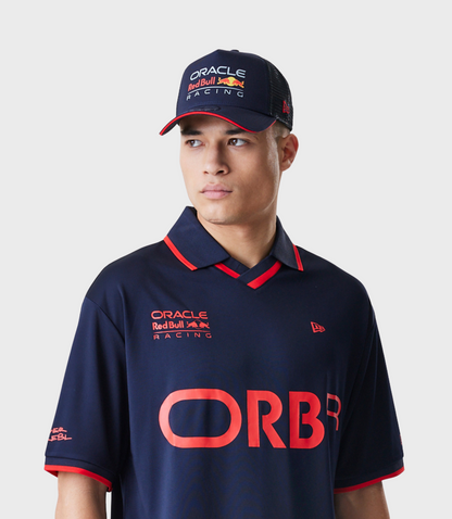 Male model in a navy Oracle Red Bull Racing polo with red trim and ORBR across the chest, wearing the Oracle Racing cap.