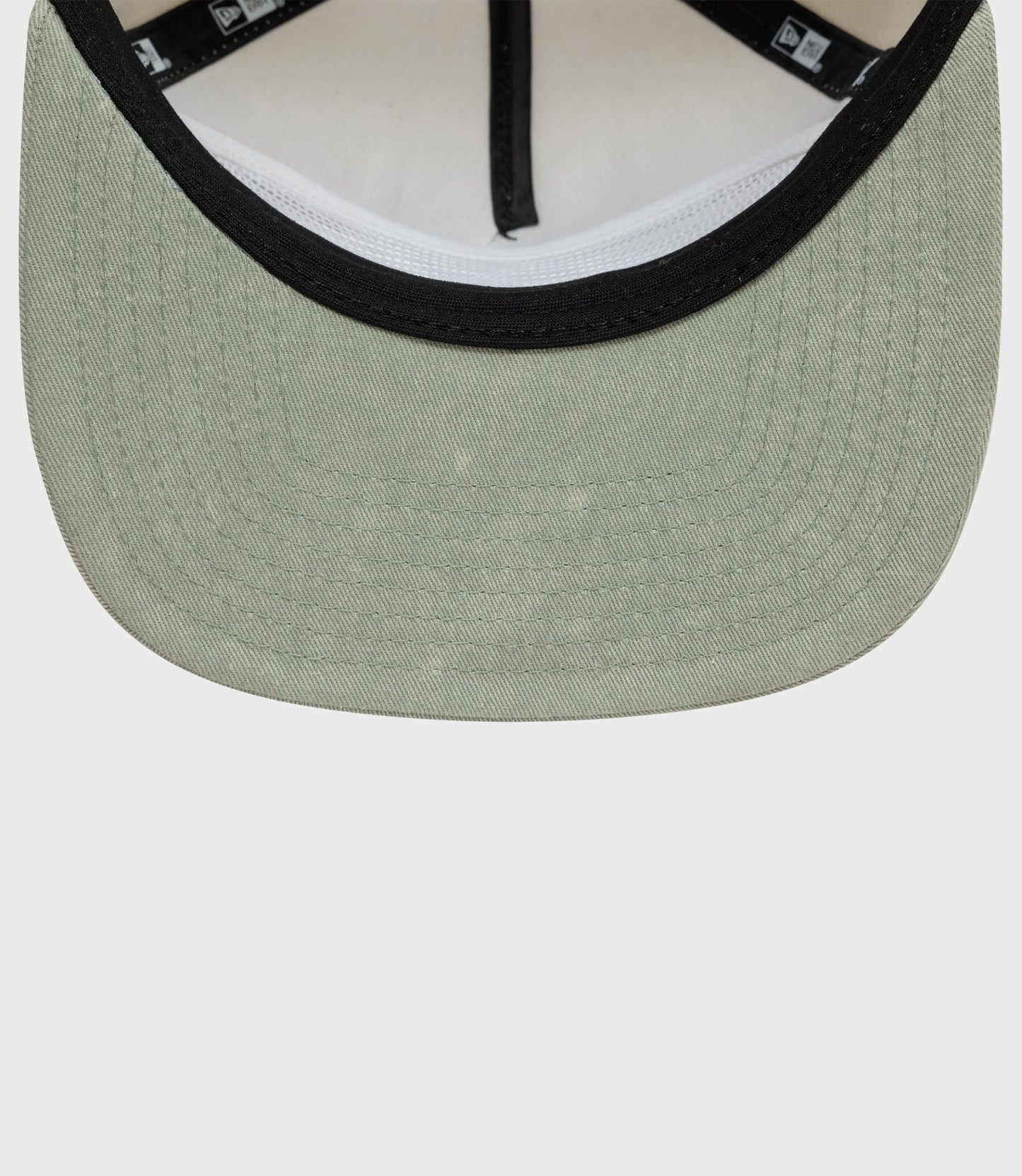 Close up of beige Alpine Acid Wash golfer cap showing black trim on the front brim.