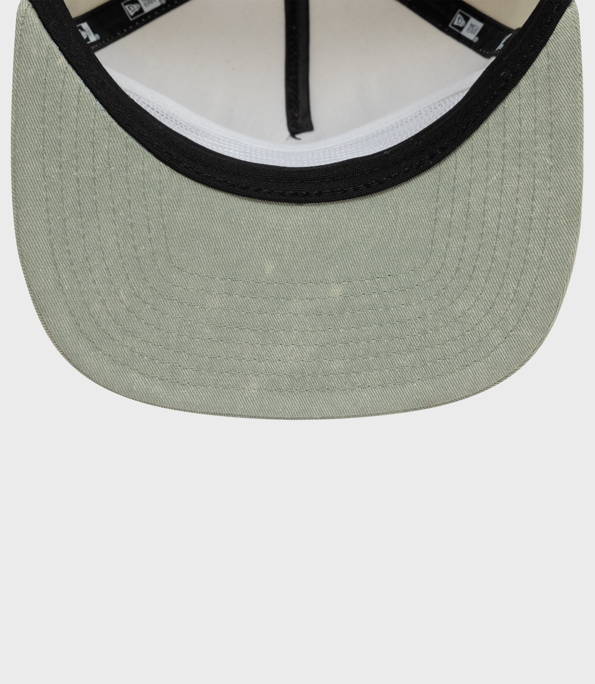 Close up of beige Alpine Acid Wash golfer cap showing black trim on the front brim.