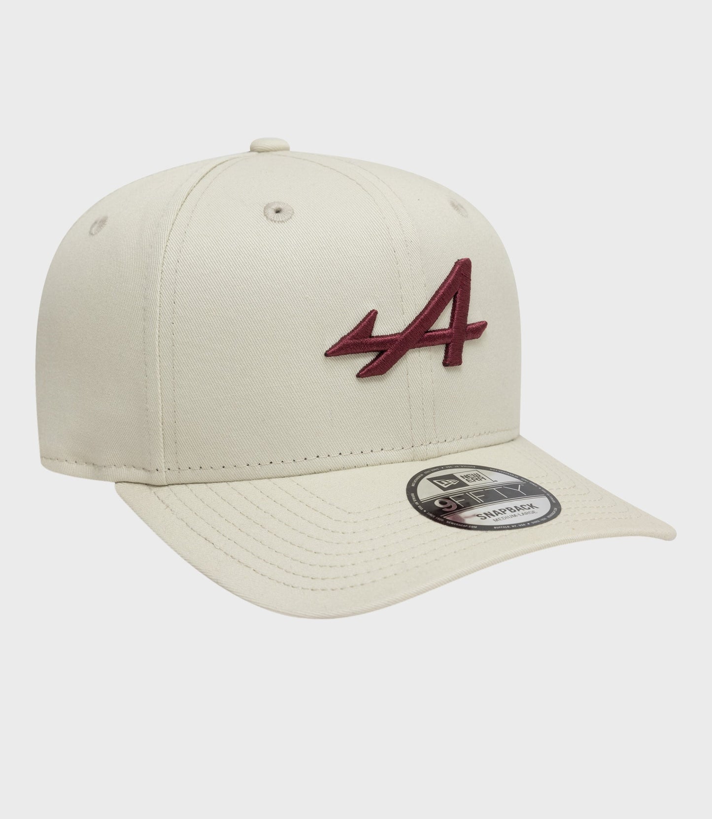 Cream New Era Alpine Seasonal 9Fifty Pre-Curve cap shown from a front side angle with burgundy embroidered logo.