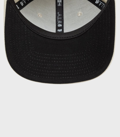 Close up of New Era Alpine 9Fifty pre curved cap in black with tan edge showing brim stitching and interior 9FIFTY branding