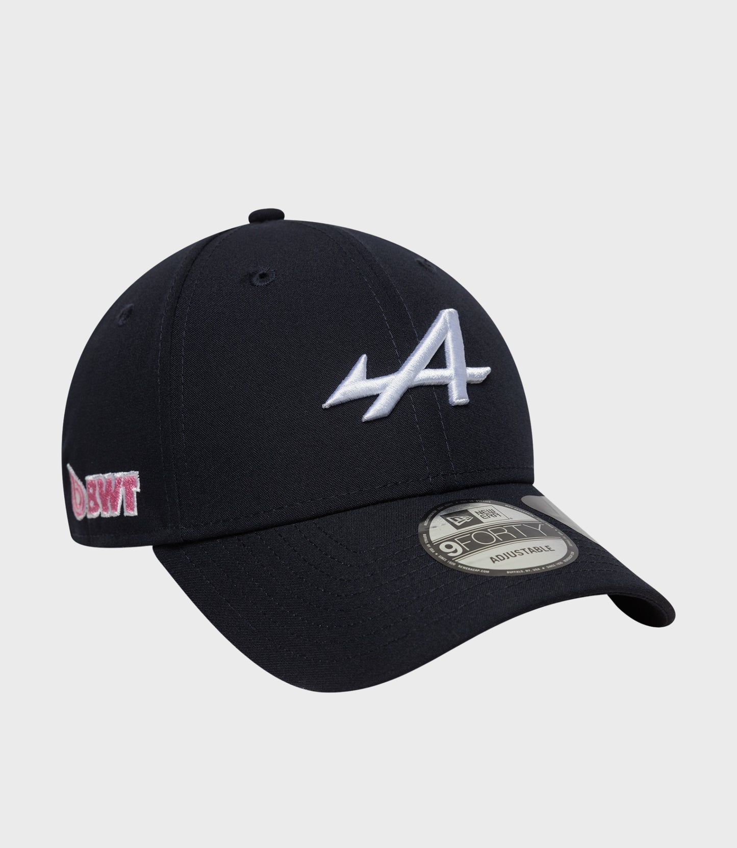 Side view of navy cap showing white front embroidery and pink patch on the side with brim sticker