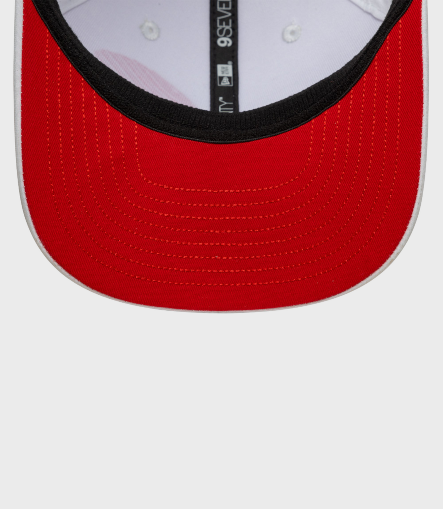 Interior close up of white cap showing black sweatband and red underside of the brim