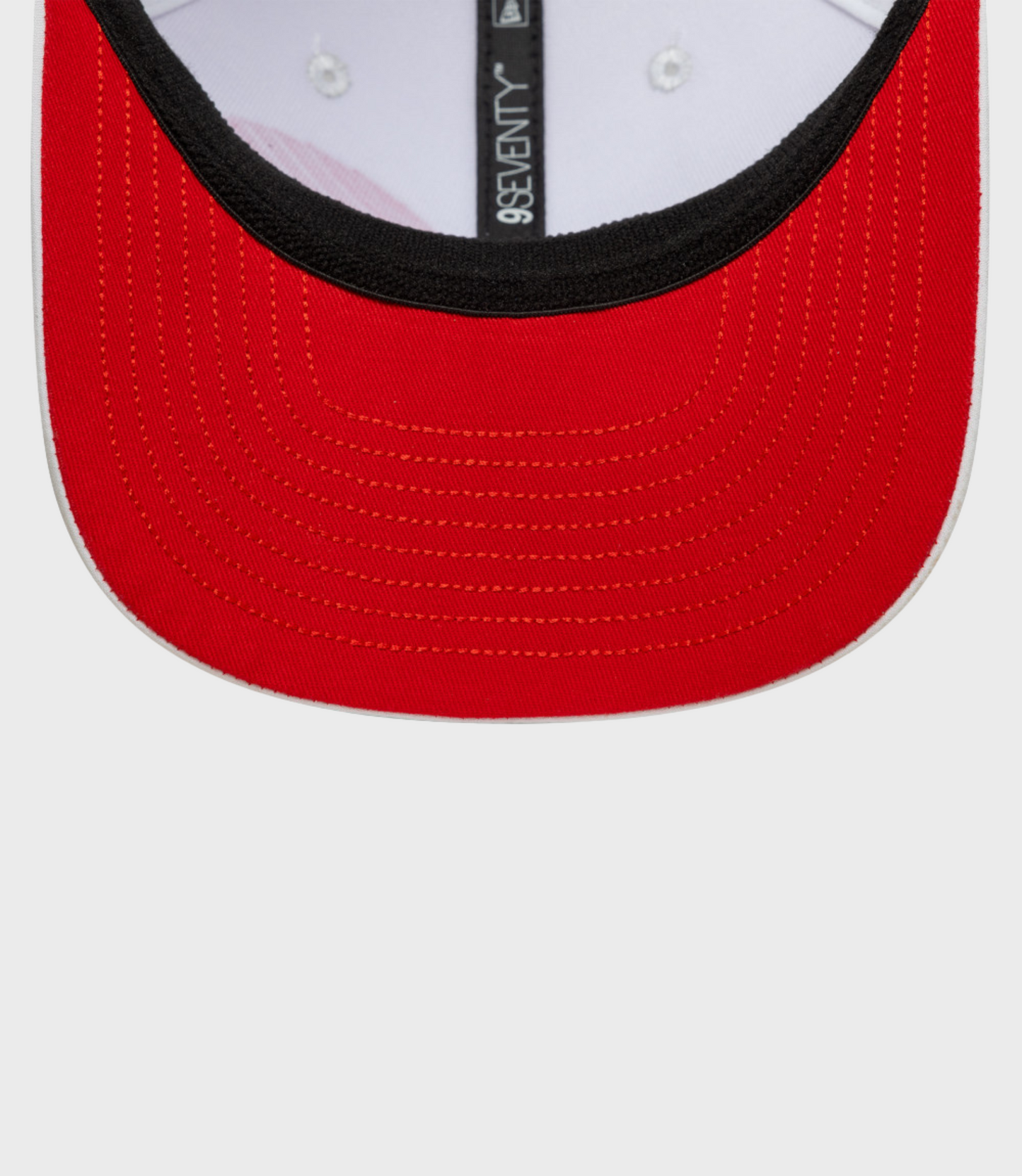 Close-up of red 9Seventy cap brim with black underbill and orange stitching