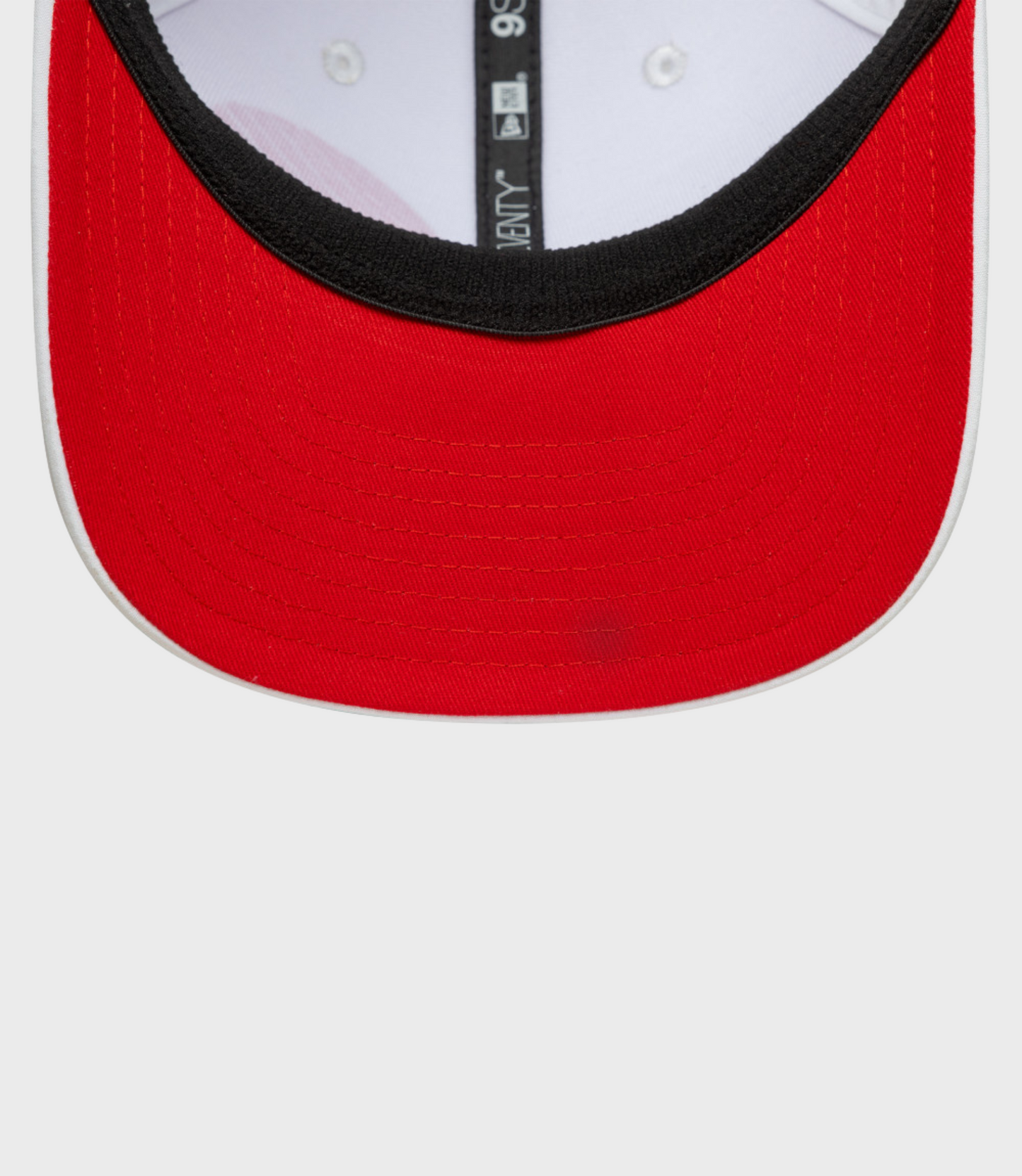 Close up of a red 9Seventy cap front panel with black edge trim and white interior, vertical tag visible