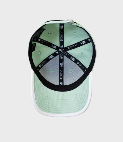 Inside view of pastel green New Era 9FORTY cap showing taped crown and interior stitching.