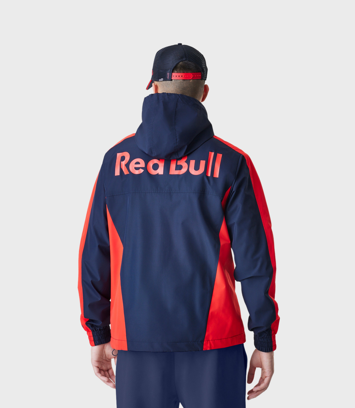Rear view of model in navy Red Bull Racing Windrunner jacket with large Red Bull lettering across back.