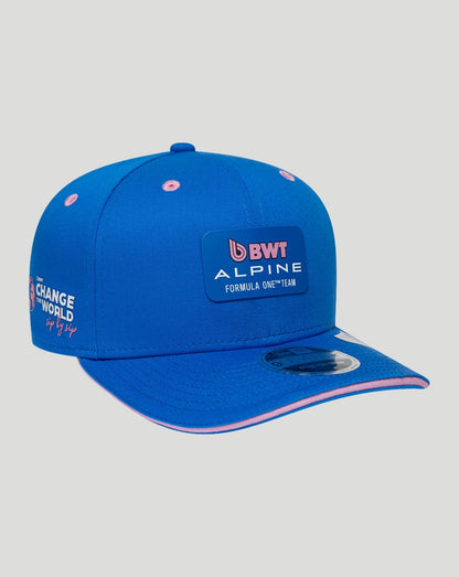 Angled view of blue New Era 9Seventy cap showing front BWT Alpine logo patch and pink brim trim