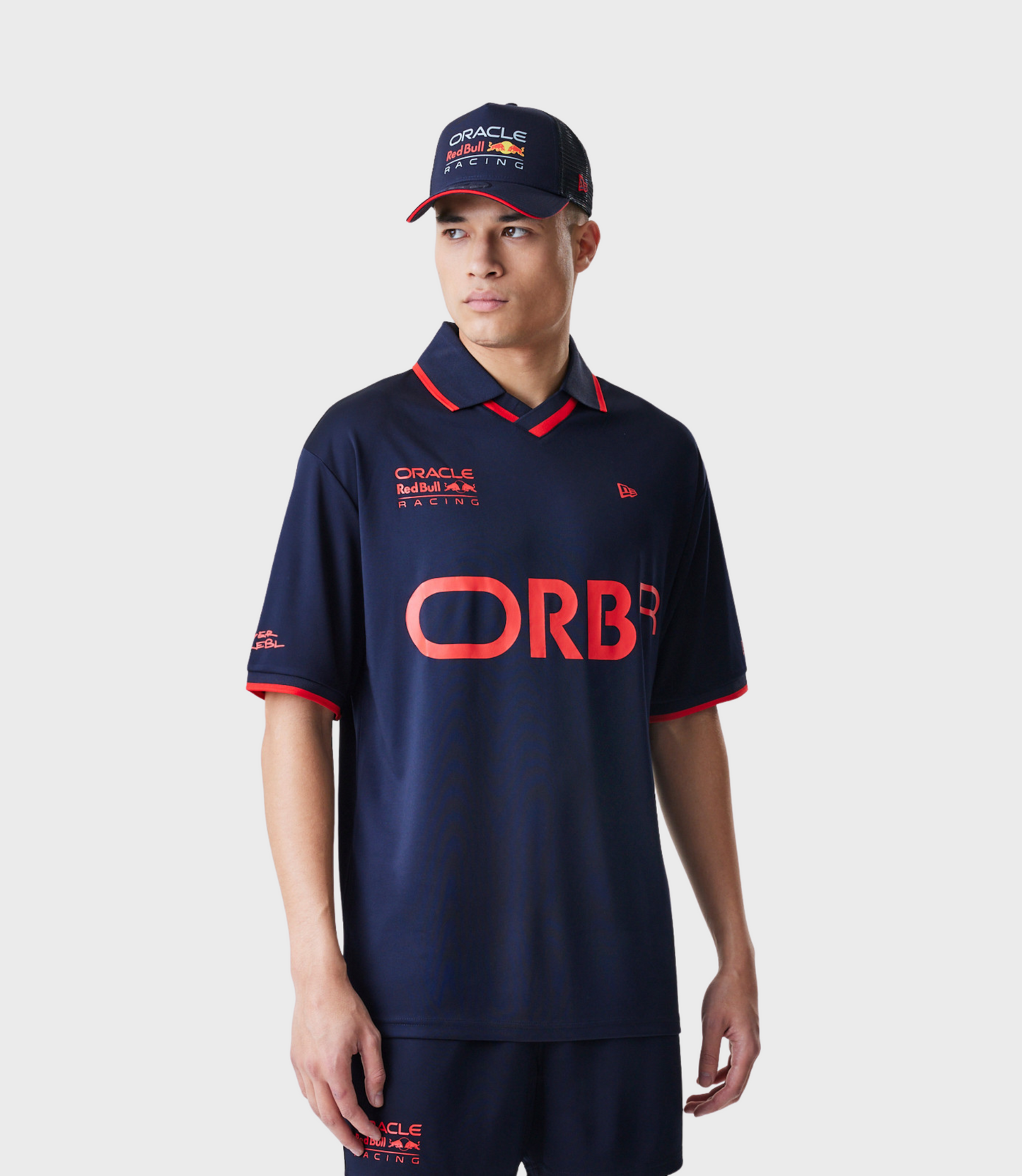 Back view of a model in a navy graphic football T shirt with ORBR lettering across the lower back