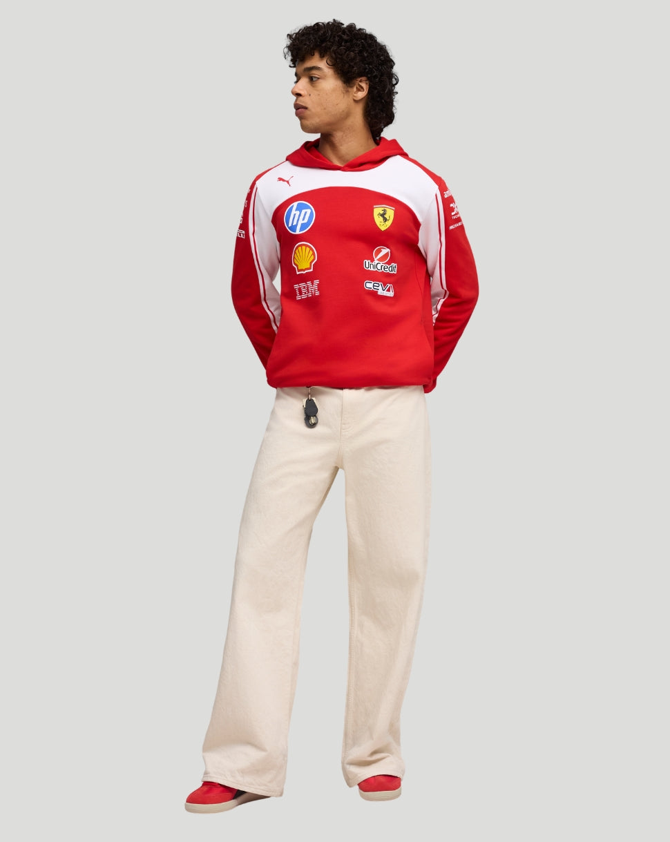 Full body side view of model in red Ferrari hoodie with white panels and sponsor logos, beige pants
