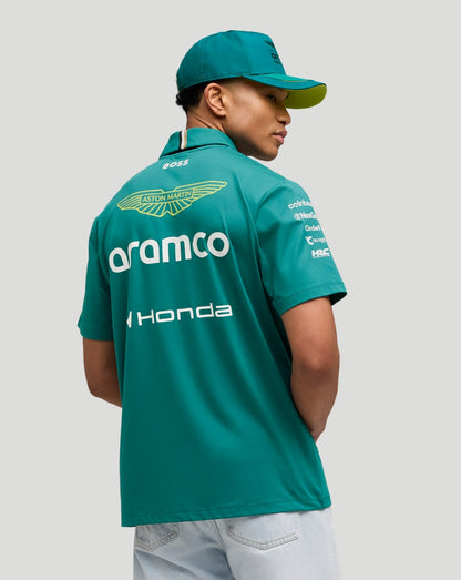 Back view of a model in green Aston Martin F1 team polo showing large sponsor logos on the back and a teal cap