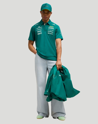 Male model wearing green Aston Martin F1 Team Polo with matching cap, holding a green jacket
