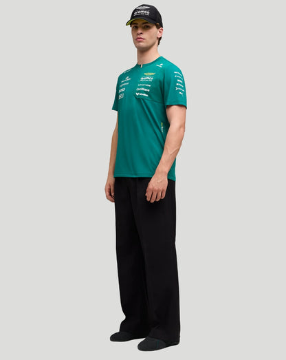 Full length side view of a male model in a teal Aston Martin F1 Team T Shirt with sponsor logos and a black cap