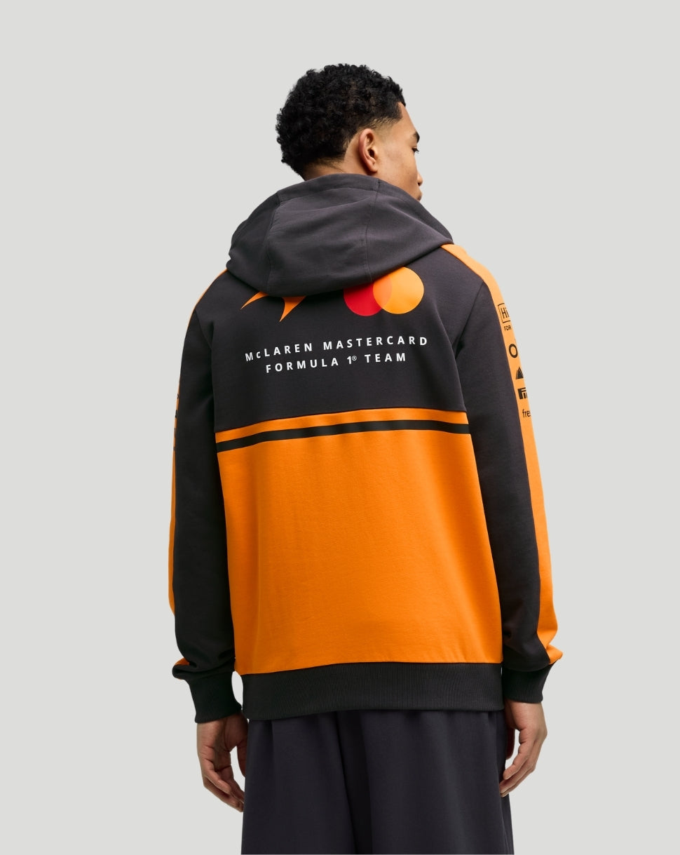 Back view of Papaya McLaren Team Hoodie in black and orange worn by a man with the McLaren Mastercard Formula 1 Team logo on the back