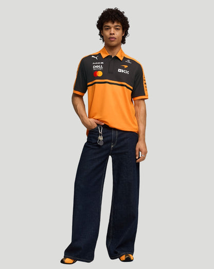 Full length front view of male model in papaya orange McLaren Team Polo with black chest panel.