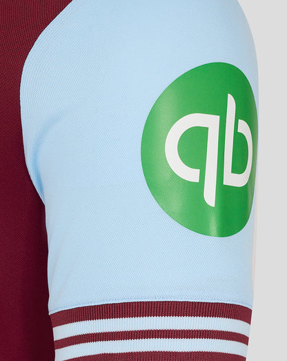 Light blue sleeve with a large green circular sponsor logo and maroon striped cuff