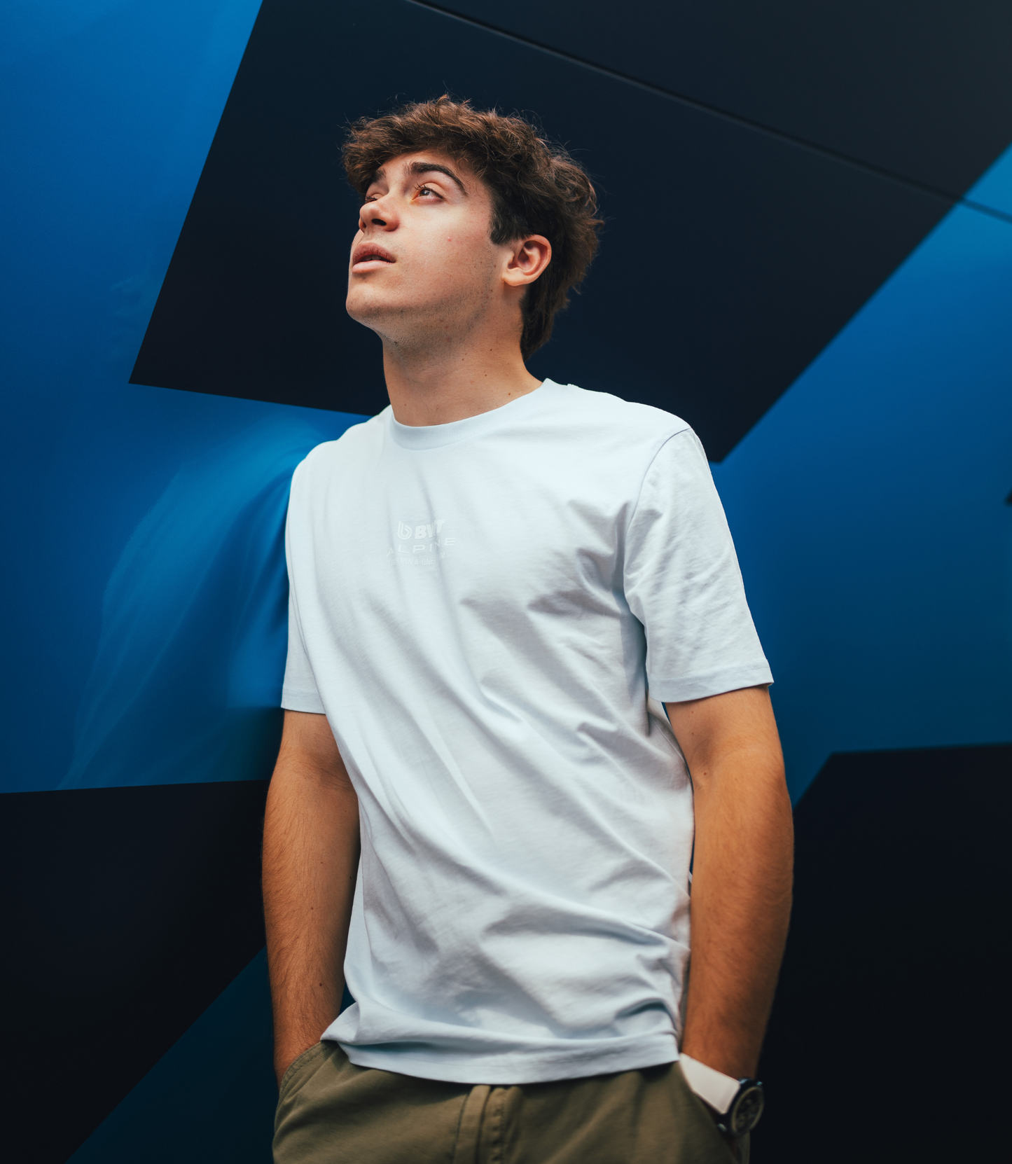 Side profile of man wearing ice blue Alpine Core Driver T shirt with small chest graphic