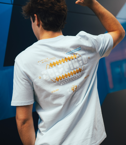 Back view of a person wearing light blue Core Driver T shirt with bold orange graphic across the back
