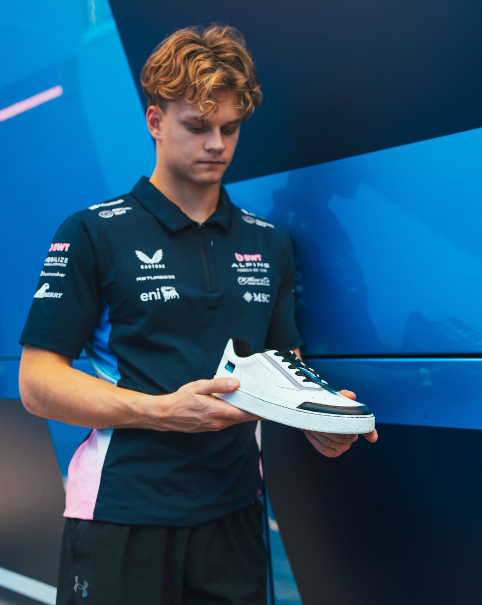 Athlete in Alpine team kit holding a white Endstate sneaker with black accents.
