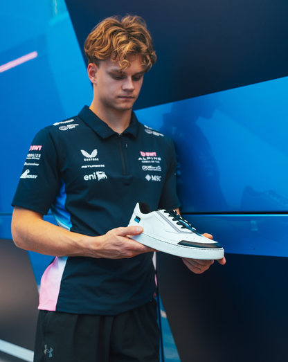 Athlete in Alpine team kit holding a white Endstate sneaker with black accents.