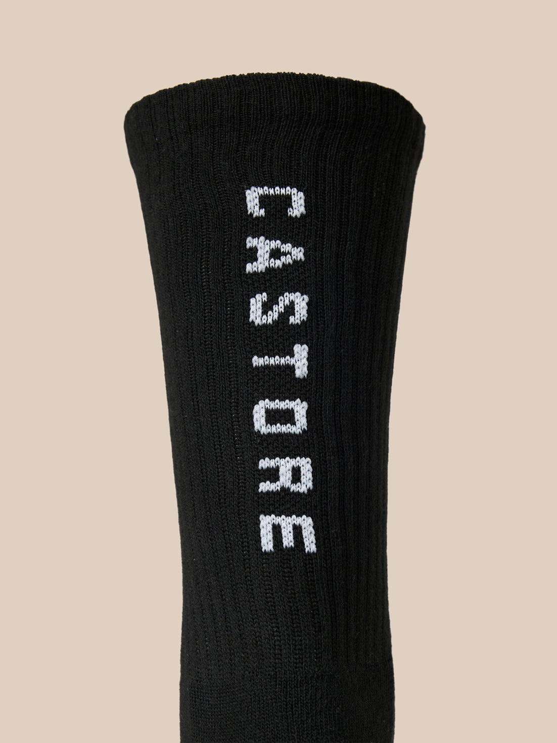 Close up of a black Castore X Ridgeway crew sock with white embroidered branding along the side