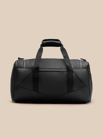 Front view of black Core Holdall with dual top handles and a detachable shoulder strap; Castore logo on front