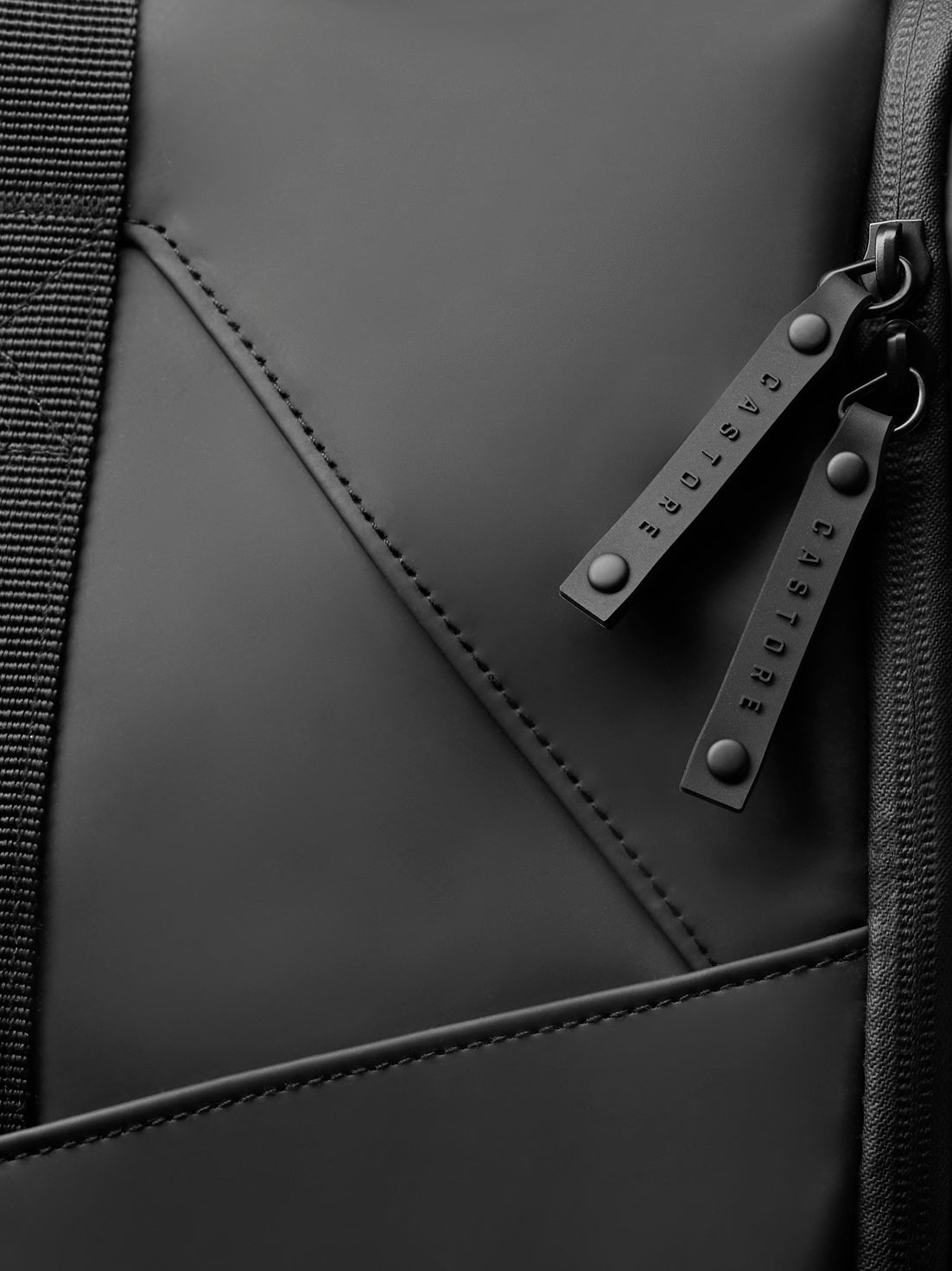 Close up of Core Holdall zipper pulls and strap in black finish with Castore branding.