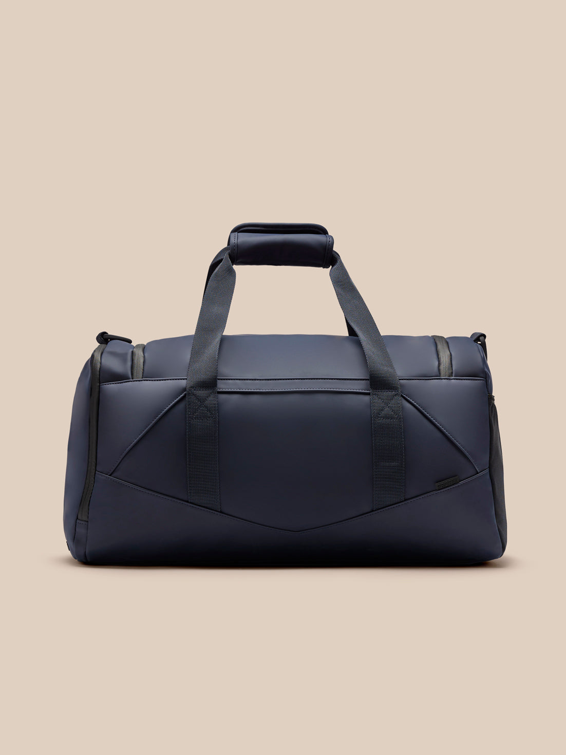 Core Holdall in navy with padded handles and an adjustable shoulder strap against a beige background