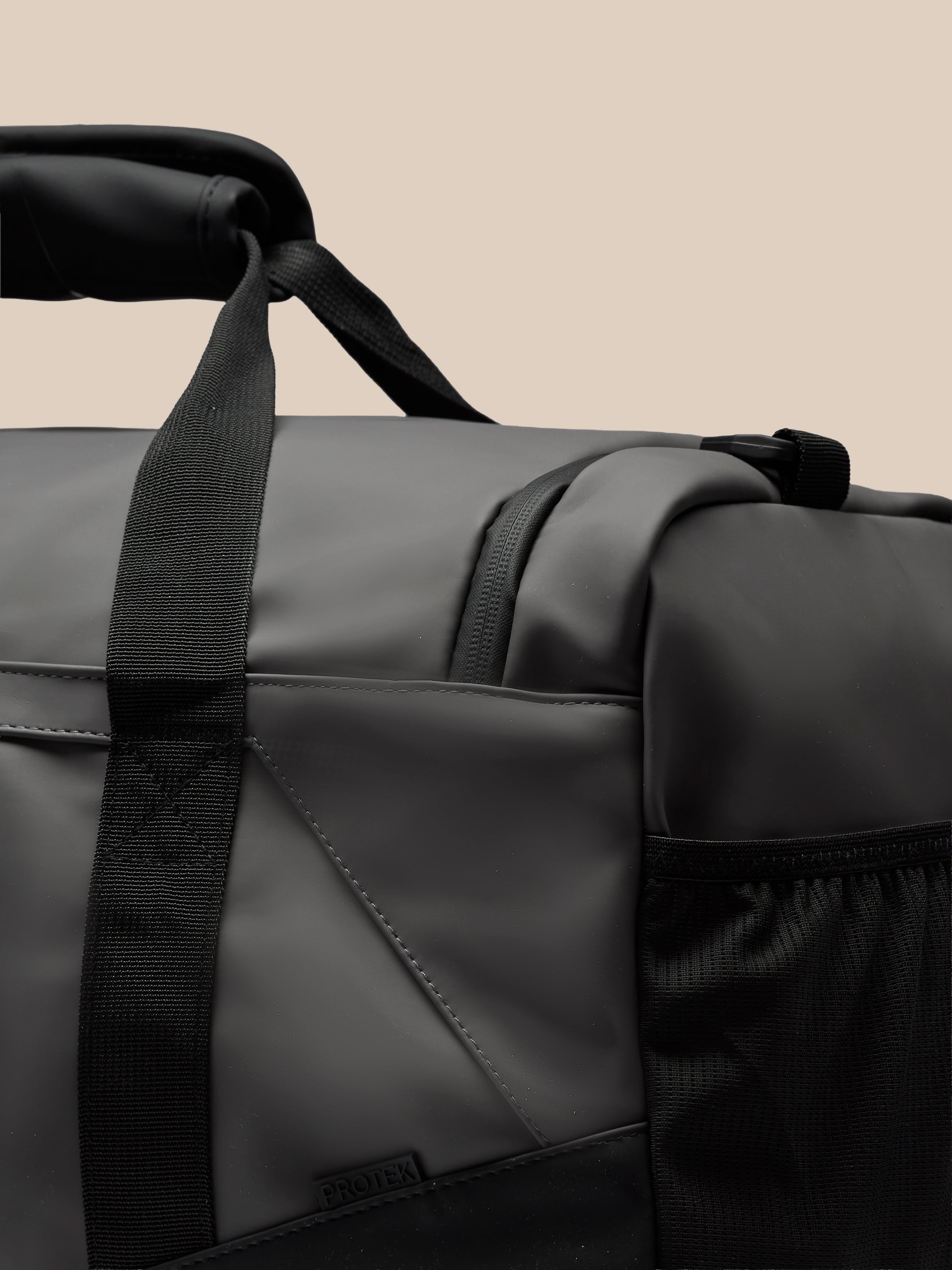 Male model in a blue gray shirt holds a large gunmetal and black Core Holdall with an adjustable strap across his body
