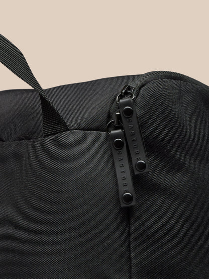 Close-up of black boot bag zipper area with two parallel zippers and Castore branding on textured fabric