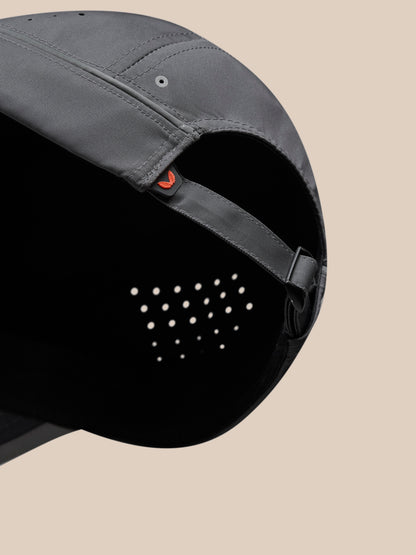 Back close-up of gunmetal cap with adjustable strap orange tab and perforated crown interior