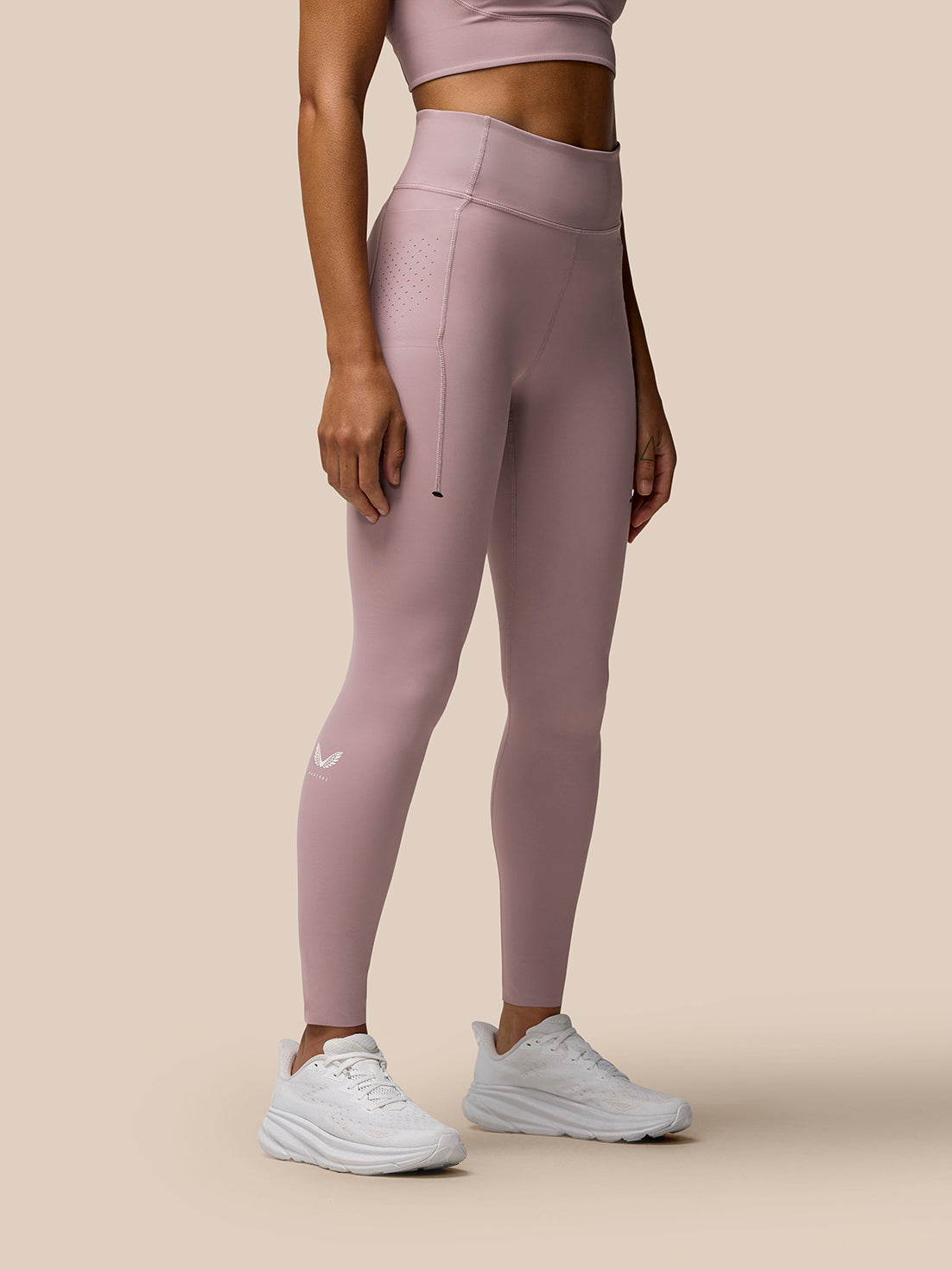Side view of a woman wearing pink Zone full-length training leggings with a high waistband and white sneakers