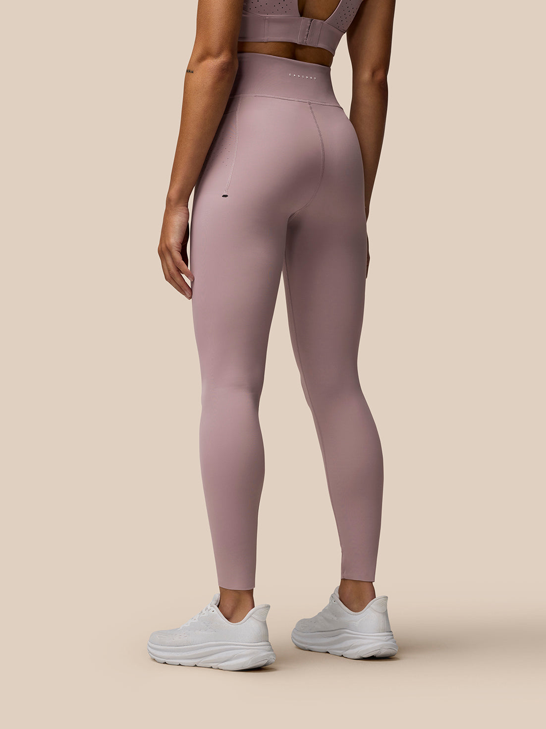 Back view of a woman in pink Zone leggings with a high waistband and visible branding on the back