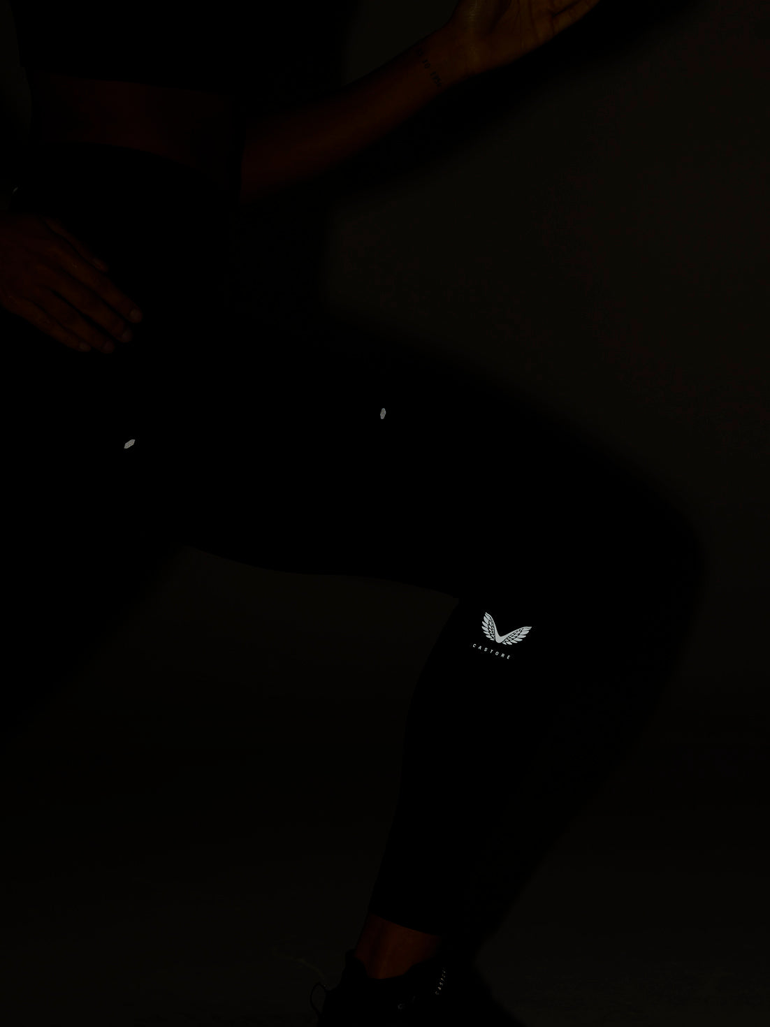 Dark shot of a person wearing black Zone Training Leggings with a small Castore logo on the thigh