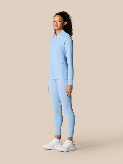 Full-body side view of a woman in sky blue Zone Training jacket and matching leggings.