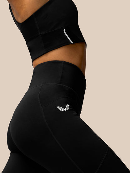 Side view of a person wearing black Apex Training Leggings with a Castore logo on the right thigh