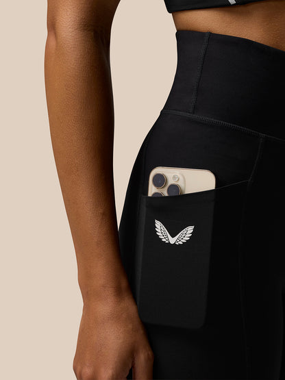 Close-up of the hip pocket on black Apex leggings with a smartphone tucked in and Castore wings logo