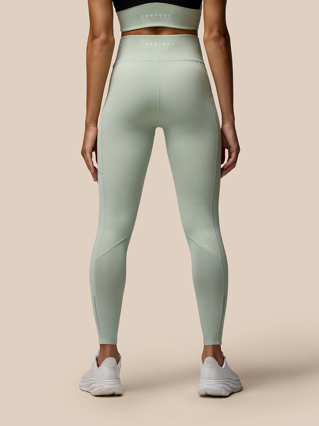 Rear view of a model wearing Sage Apex Full-Length Training Leggings with Castore branding on the right thigh.