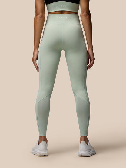 Rear view of a model wearing Sage Apex Full-Length Training Leggings with Castore branding on the right thigh.