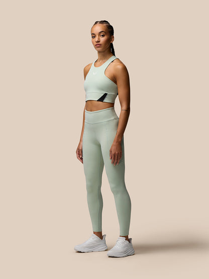 Female model wearing Sage Apex training leggings and matching sports bra in a studio setting.
