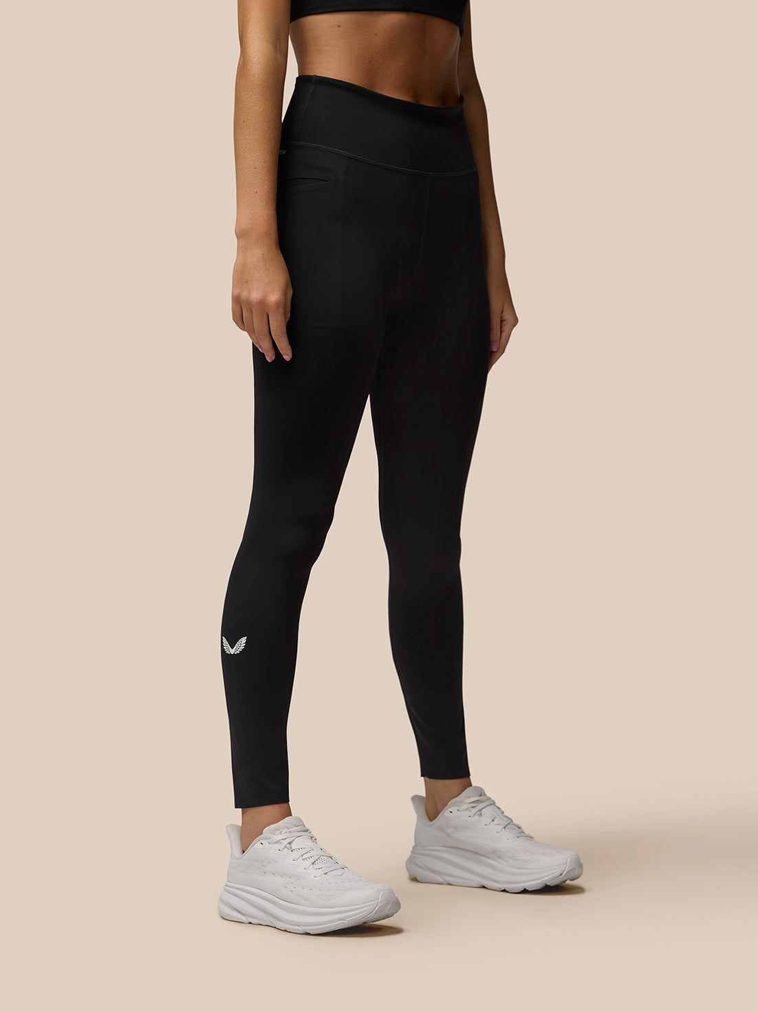 Back view of black Flow Movement leggings on a model with leg pocket detail and calf logo